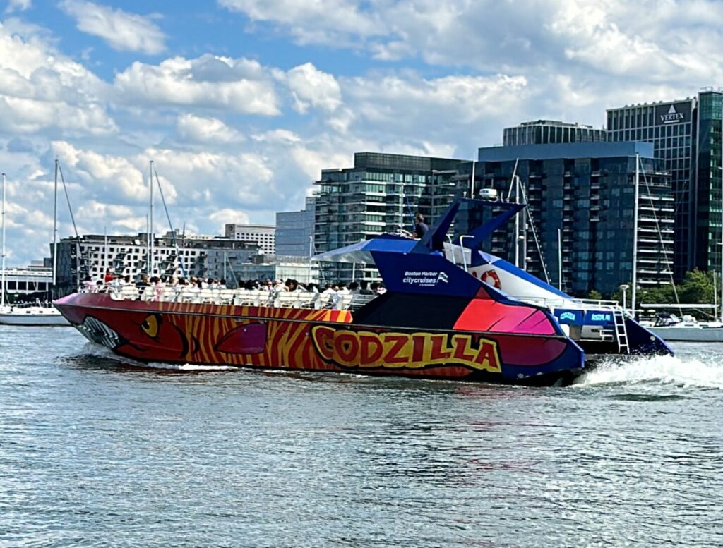 View of the side of the Codzilla as it heads out to sea with passengers in ponchos.