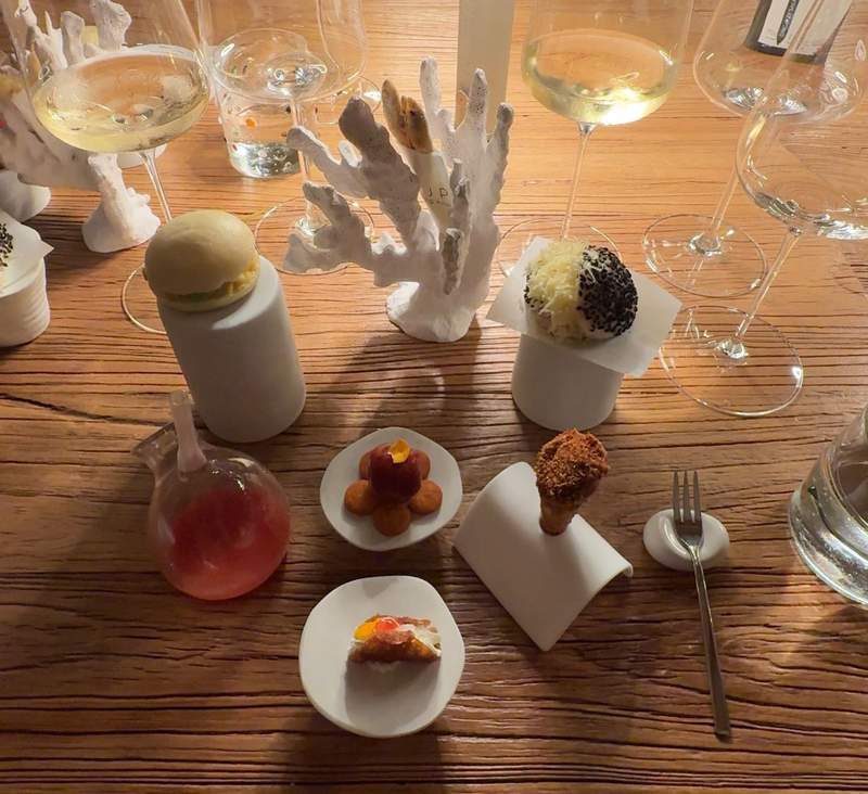 A table holds 7 different small bites of creatively presented appetizers at I Pupi Ristorante in Bagheria. 