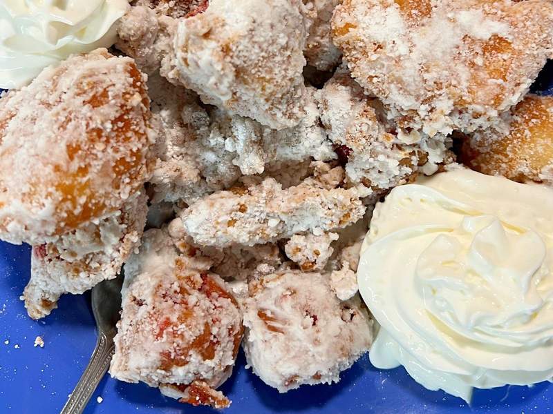 Apple and strawberry fritters on a blue plate.