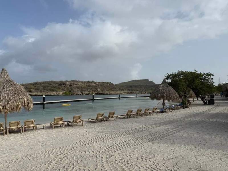 Beach with beach chairs and grass umbrellas