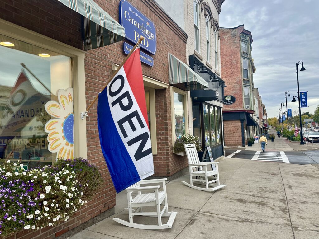 Red, white and blue "Open" flag hanging from a storefront on Canandaigua, New York Main Street.