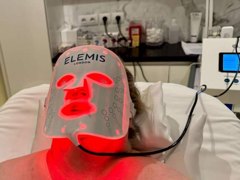 Lady lays on a spa bed with an infrared face mask.