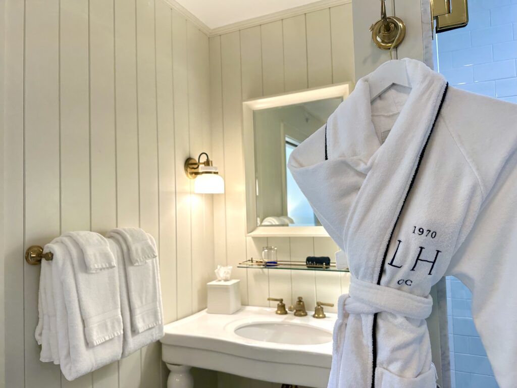 Vintage style washstand sink with mirror, towels and robe featuring the Lake House on Canandaigua logo.