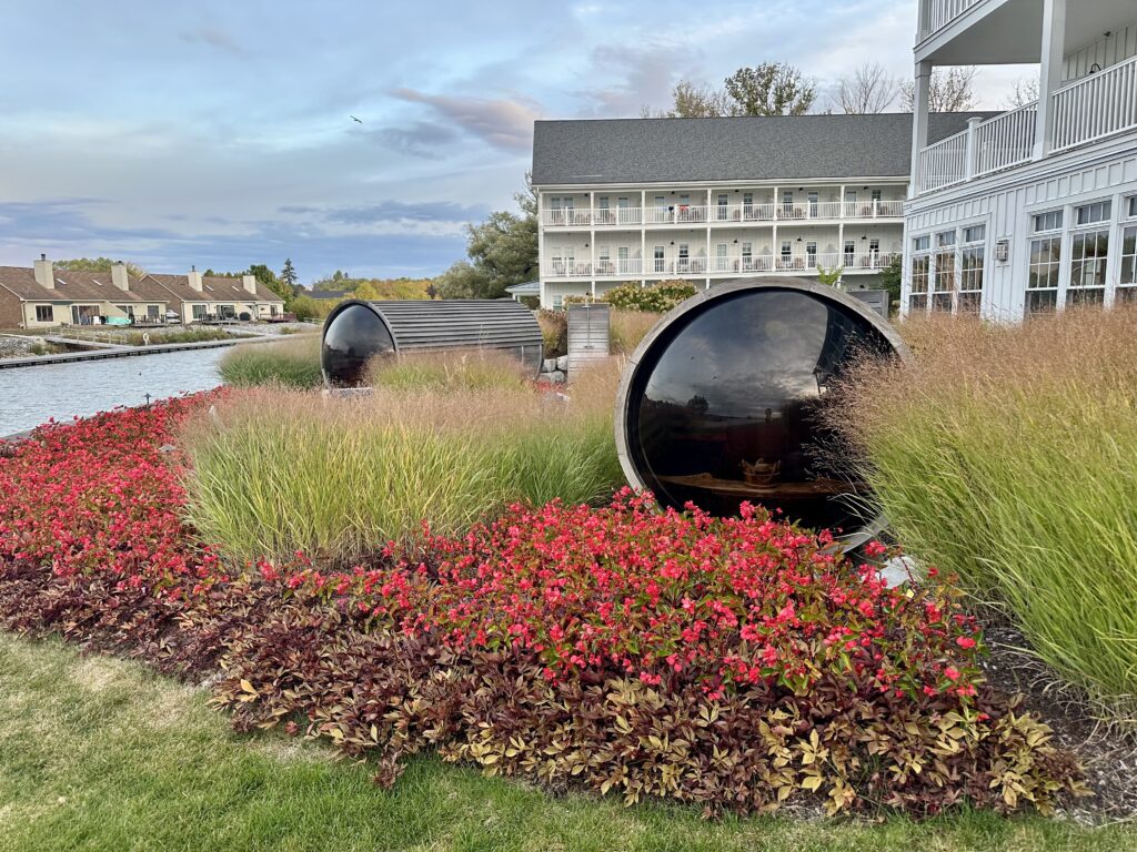 Two barrel saunas in a landscaped garden in front of cottage buildings at the Lake House on Canandaigua