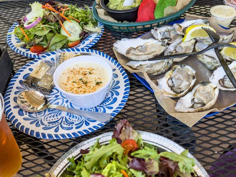 Lunch spread at Ocracoke Oyster Company: oysters on the half shell, crab soup, garden salad, and chips with guacamole.