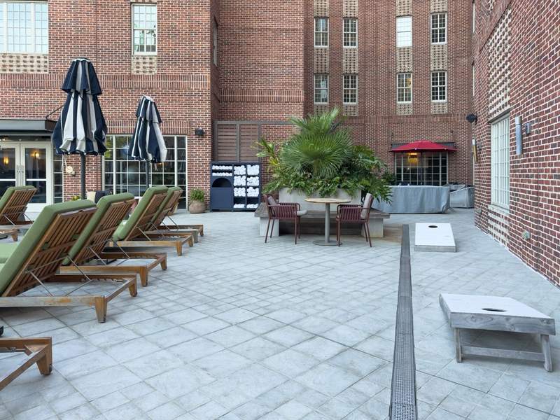 Outdoor pool and entertainment area at The Alida Hotel in Savannah, Georgia, featuring lounge chairs, cabanas, and stylish design.