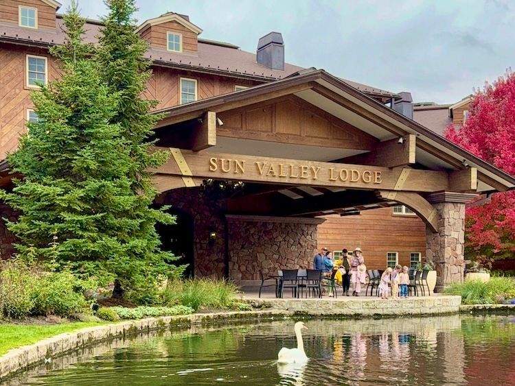 Sun Valley Lodge entrance with stone architecture, mountain backdrop, and a swan gliding across the front pond.