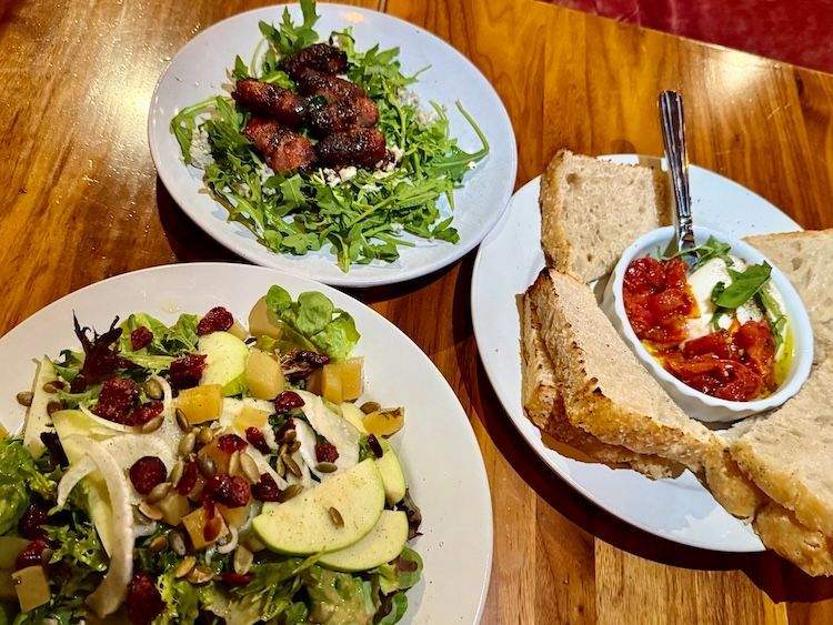 Three small plates of appetizers on a wooden table at Enoteca restaurant in Ketchum, Idaho.