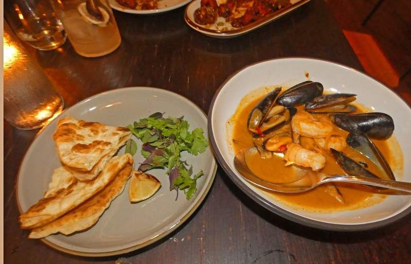Two dishes one with pita bread and lettuce and other with mussels and shrimp.