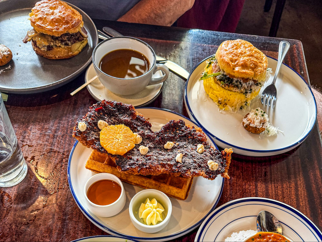 Plates of biscuits and chicken and waffles on a wooden table at an Atlanta restaurant