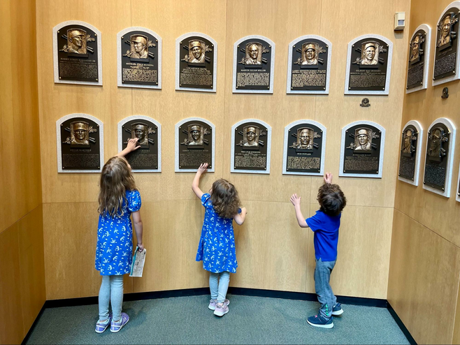 Three children examine bronze plaques of Hall of Famers in the Plaque Gallery at the National Baseball Hall of Fame and Museum in Cooperstown, New York.