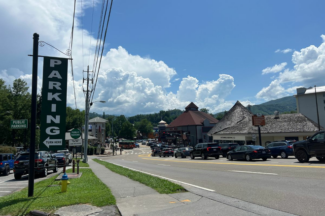 Outskirts of a town with mountain themed buildings and a line of cars heading into the town.