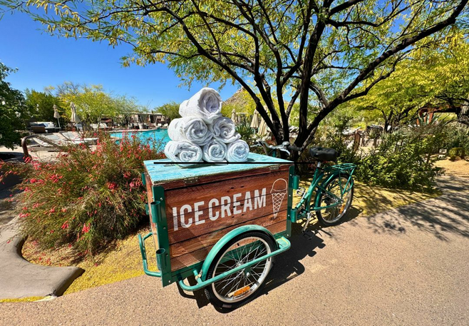 Vintage-style ice cream cart topped with rolled towels by the poolside