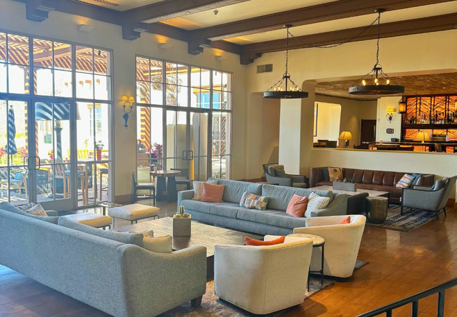 Spacious, sunlit lobby with modern desert-inspired decor at Four Seasons Scottsdale at Troon North, featuring comfy seating and large windows overlooking an outdoor patio