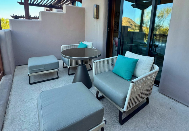 Modern outdoor patio with cushioned chairs and a table outside a casita at Four Seasons Scottsdale, with desert reflections in the glass door