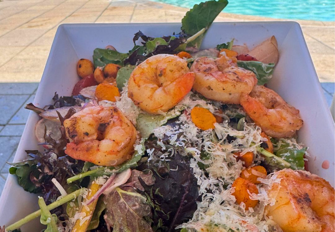 Close-up of grilled shrimp salad with mixed greens, cheese, and crispy toppings served poolside at Four Seasons Scottsdale