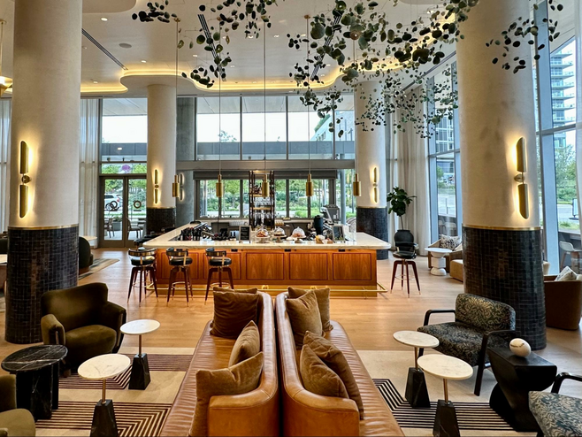 Chestnut couches in the lobby and bar of the HALL Park hotel in Frisco, Texas, located near the city's Kaleidoscope Park features a suspended art installation that resembles floating butterflies.