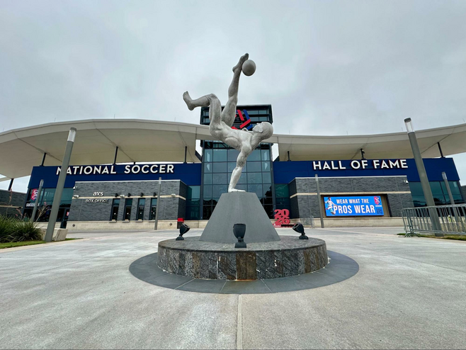 Dramatic silver sculpture of a soccer player making a kick outside the National Soccer Hall of Fame in Frisco, Texas, a fun venue to visit on a sports getaway.