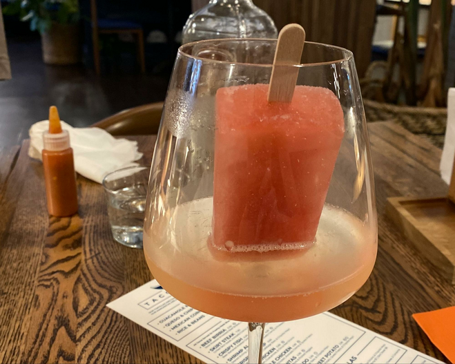 pink popsicle in a wine glass with wine.