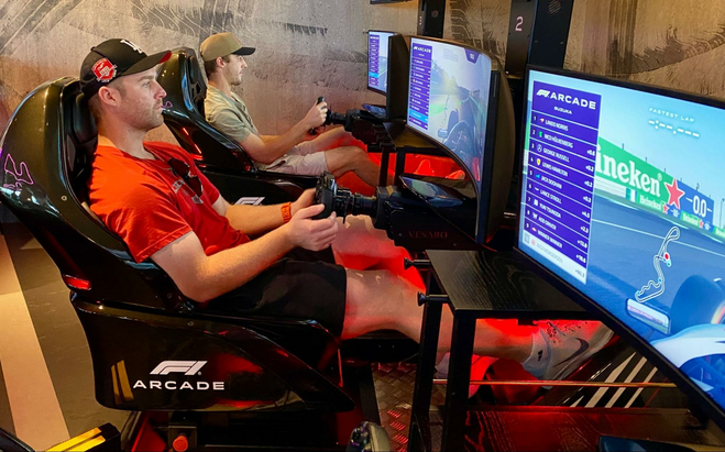 two guys in video game seats playing video games on a big screen.