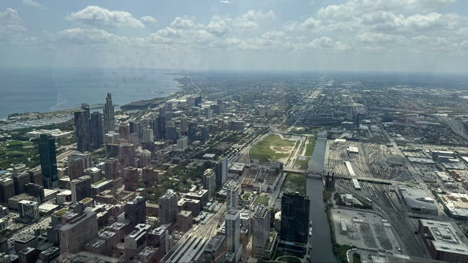 Birds eye view of skyscrapers and a river with clouds floating above.