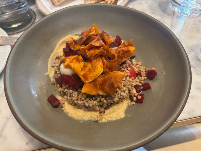 Vegan food with fried sweet potatoes on a bed of barley and beet, with bean curd spread