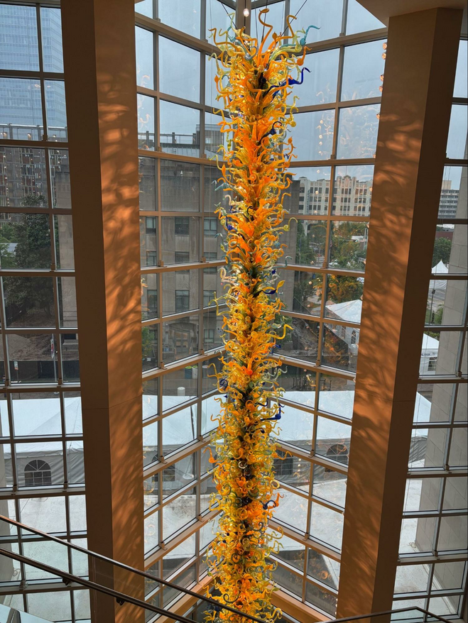 multi-story tree of Chihuly glass inside a window overlooking the city skyline