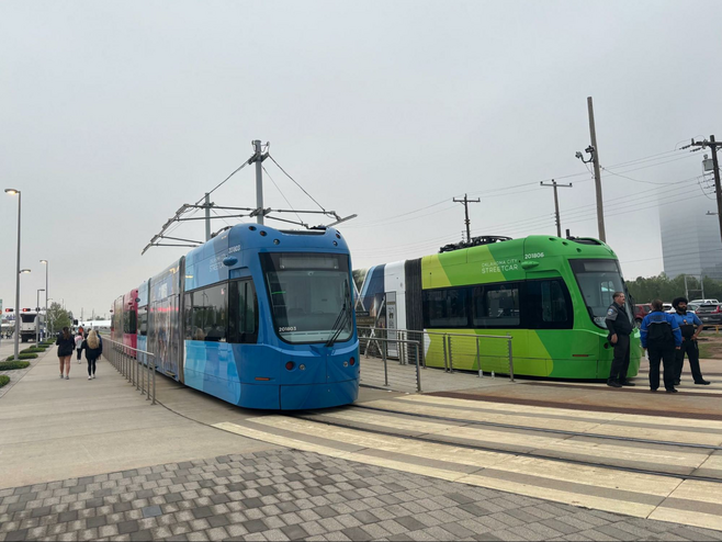 Two streetcars with pedestrians and streetcar staff