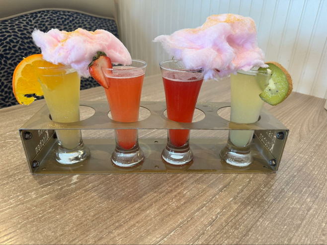 colorful mimosas in a silver tray with cotton candy and fruit on top