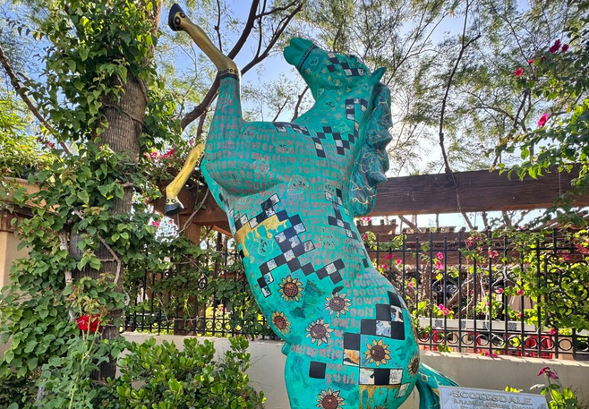 A statue of a teal horse on its hind legs in Scottsdale