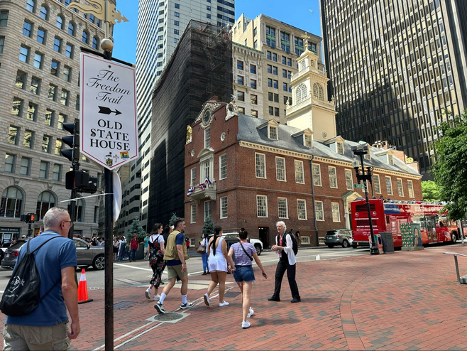 Things to do in Boston include taking a food tour which also incorporates some of the city's history. Tour group walks along the Freedom Trail toward the Old State House.