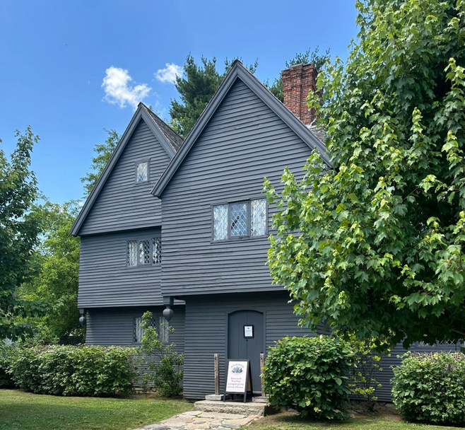 View of the House of the Seven Gables with lawn and walkway in front and bushes and trees.