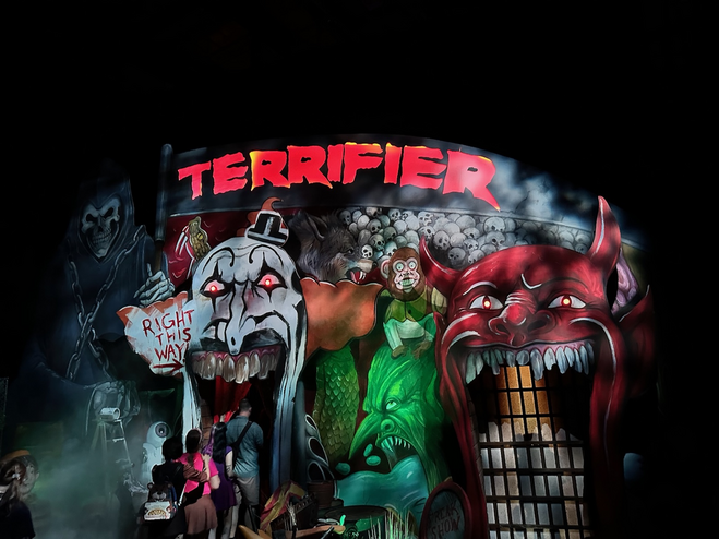 Haunted house exterior with giant clown and evil toys.