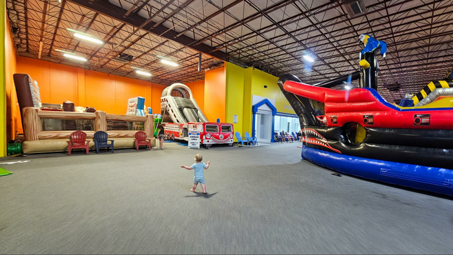 a toddler walking around an indoor bounce house 