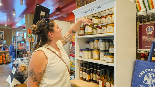 A woman poking through gourmet grocery items at a shop 