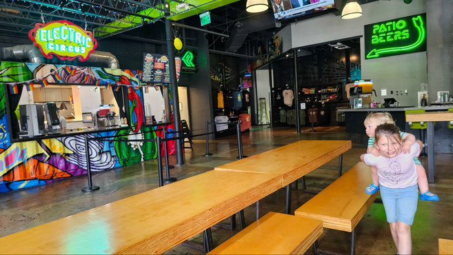 A sister giving her younger brother a piggyback ride in the Precarious Beer Hall. 