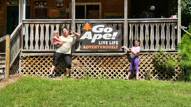 a mother with her two children in front of the business sign of Go Ape