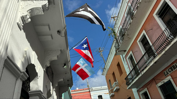 Three flags waving in the air on a colorful street in Old San Juan, Puerto Rico.