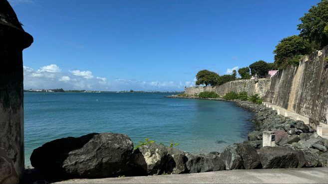 Rocks lined up near a body of bright blue water.