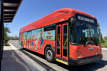 Red Universal Orlando shuttle bus with Nintendo characters painted on the outside.
